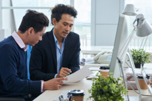 Two Asian compliance professionals reviewing AML obligations and documentation at a financial institution in Japan