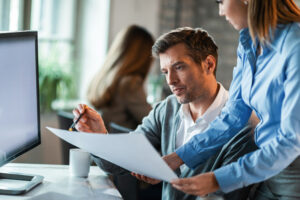 Two business compliance professionals examining APTCP documentation and AML law requirements for Japanese financial institutions
