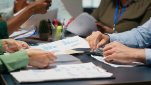 Multiethnic compliance team reviewing travel rule infographics and cross-border payment obligation solutions for Japanese financial institutions