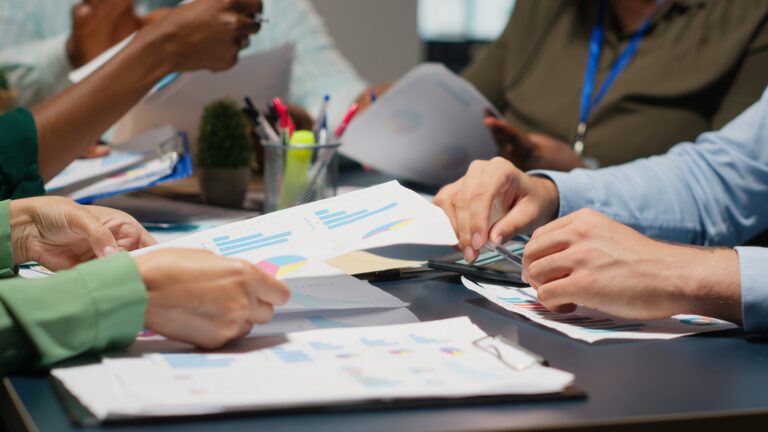 Multiethnic compliance team reviewing travel rule infographics and cross-border payment obligation solutions for Japanese financial institutions