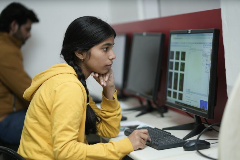 Compliance researcher focused on a monitor analysing data panels, representing adverse media screening review