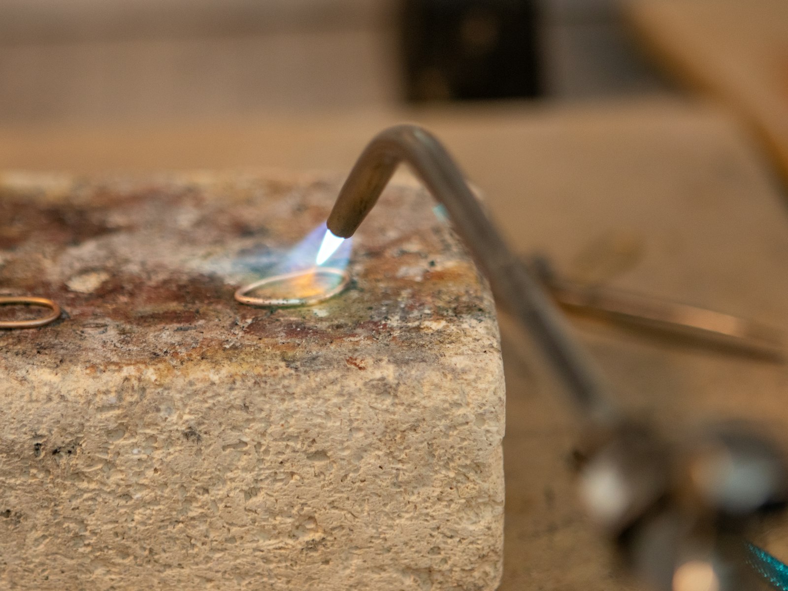 Professional goldsmith workshop showing jewellery soldering process, representing AML compliance obligations for precious metals and stones dealers in the UAE